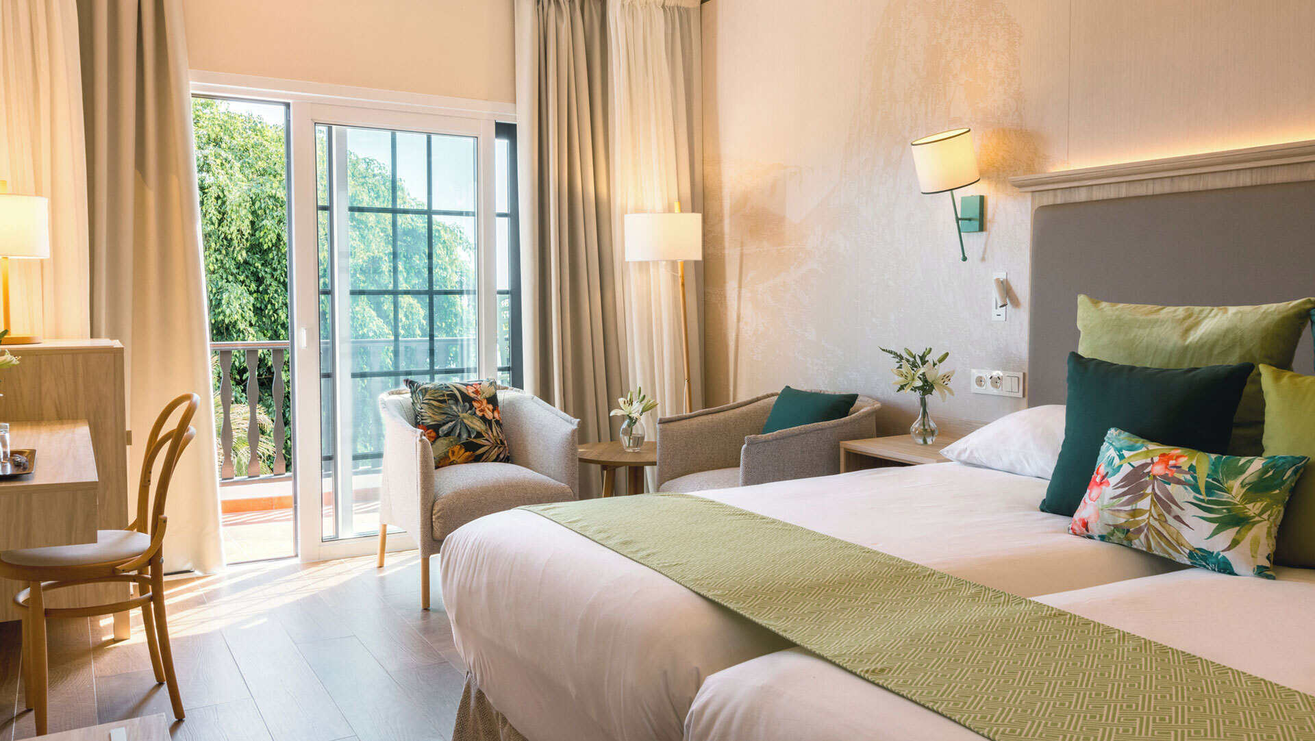 Freundlich eingerichtetes Zimmer im Hotel Jardín Tecina mit Doppelbett, Sitzecke und Zugang zur Terrasse.