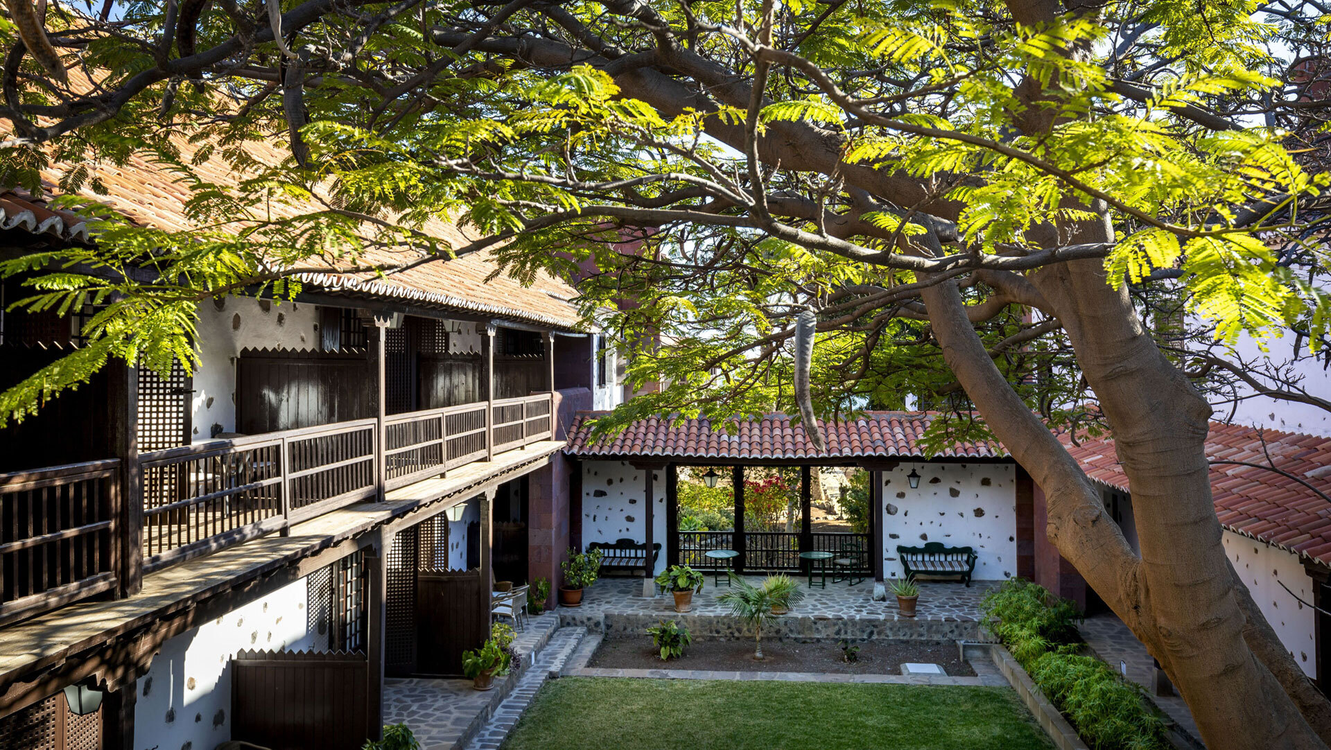 Der begrünte Innenhof des Parador Conde de la Gomera mit traditioneller Holzgalerie und gepflegtem Garten.