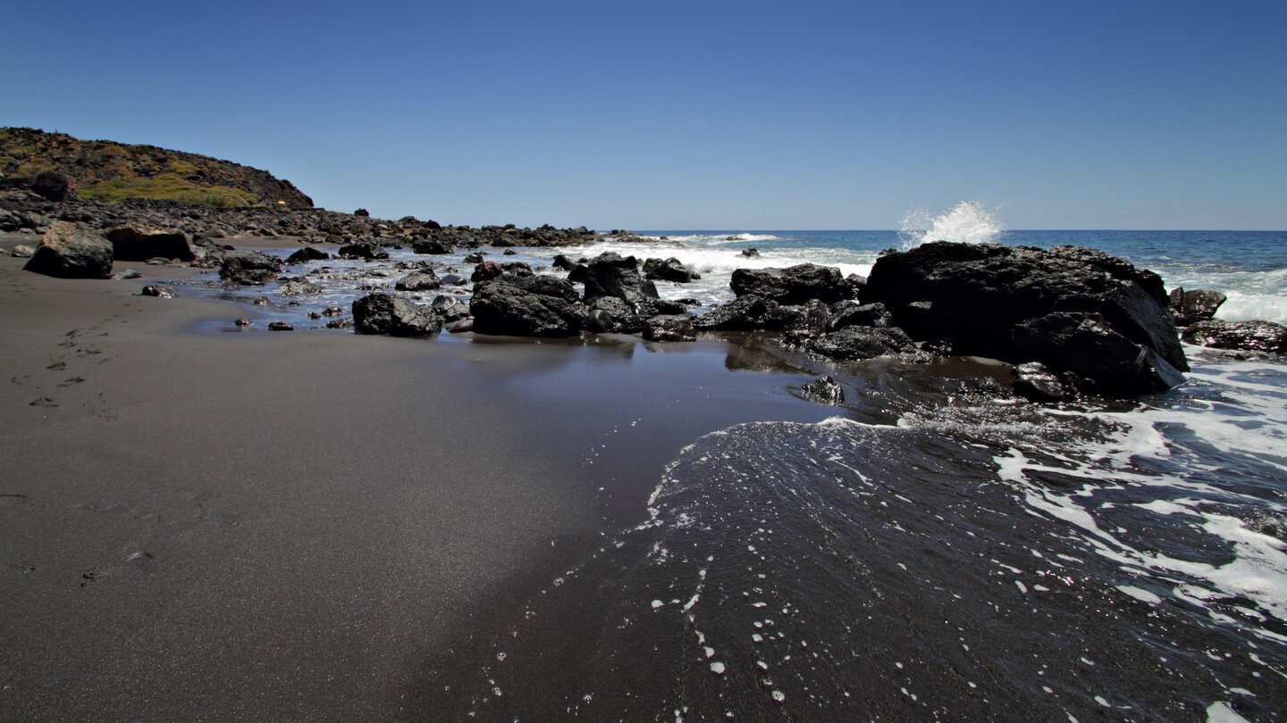 Blick entlang des schwarzen Sandstrands an der Playa del Inglés auf La Gomera