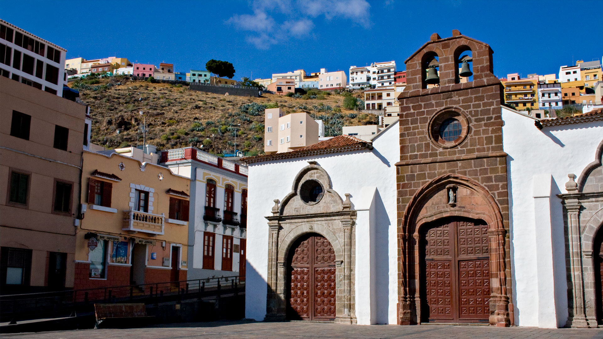 Historische Iglesia de la Asunción mit reich verziertem Sandsteinportal, im Hintergrund die bunten Häuser San Sebastiáns.