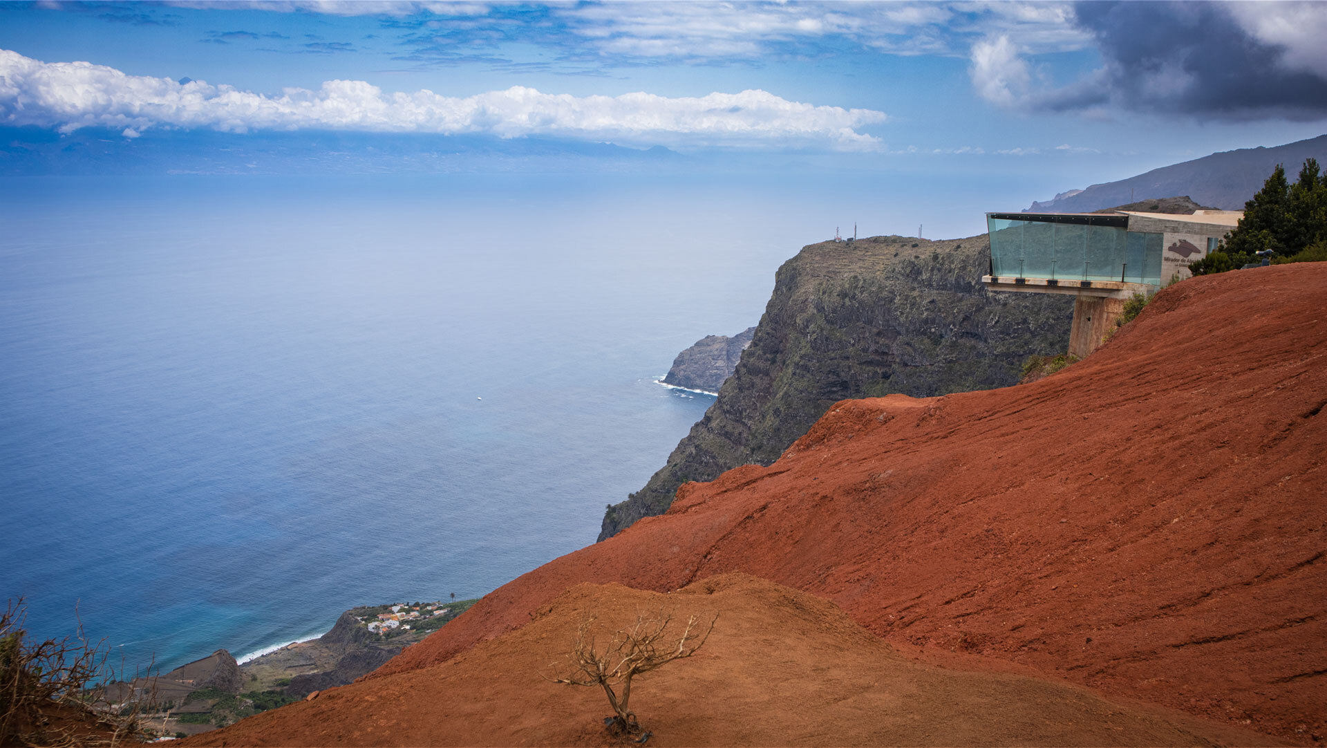 hinter den leuchtend roten Erosionsflächen des Mirador de Abrante erhebt sich Teneriffa am Horizont