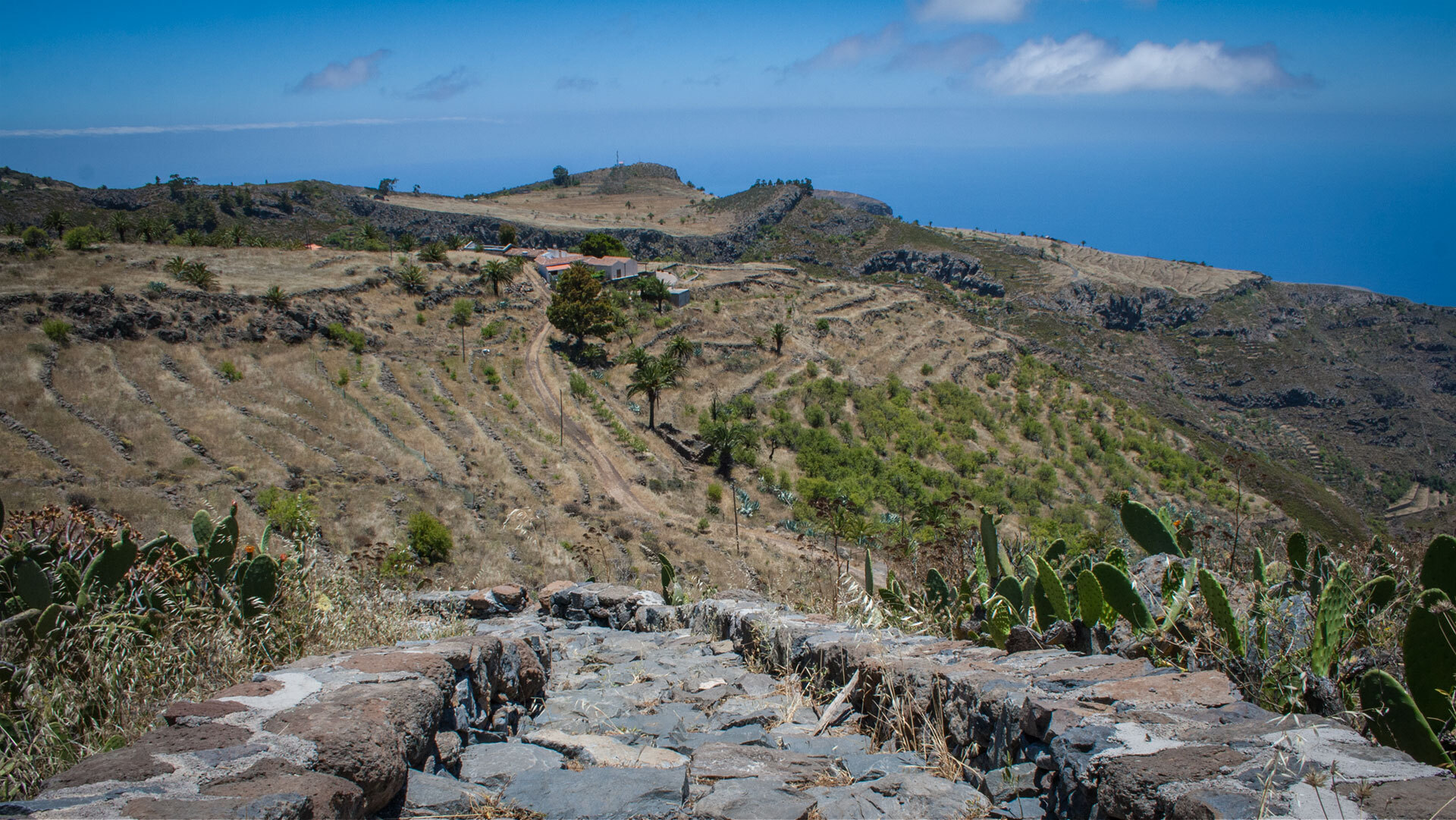 Ein alter Steinweg führt durch terrassierte Hänge bei Imada, mit weitem Blick über die Landschaft bis zum Atlantik.