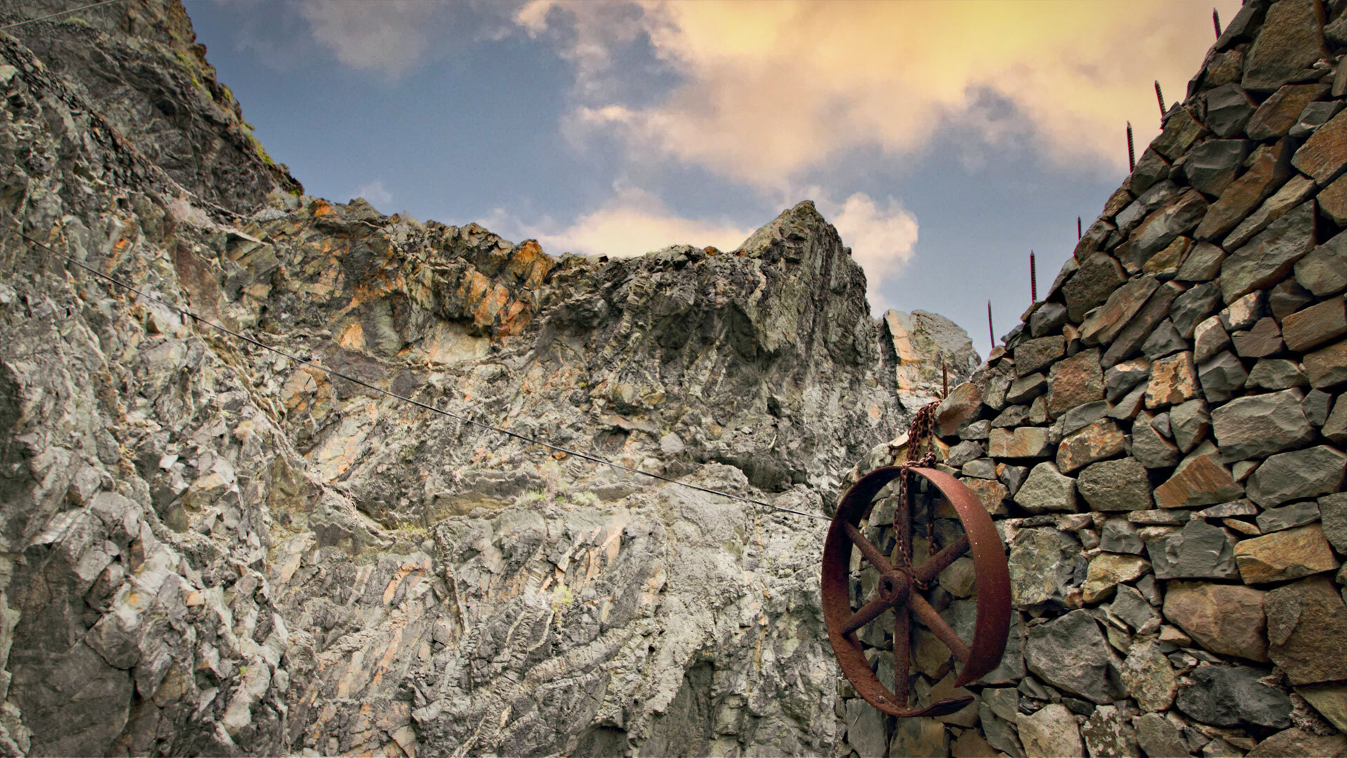 Der Zugangsweg zum Castillo del Mar führt vorbei an einer Steinmauer mit rostigem Seilrad, eingerahmt von zerklüfteten Felswänden.