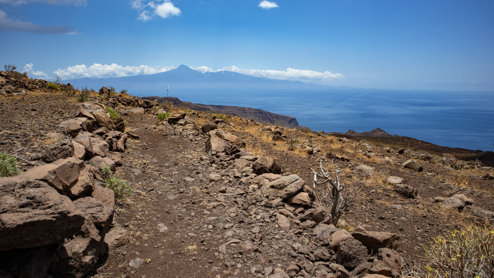 An dieser Wegpassage des GR-132 auf La Gomera zeigt sich im Hintergrund die Silhouette Teneriffas mit dem Teide.